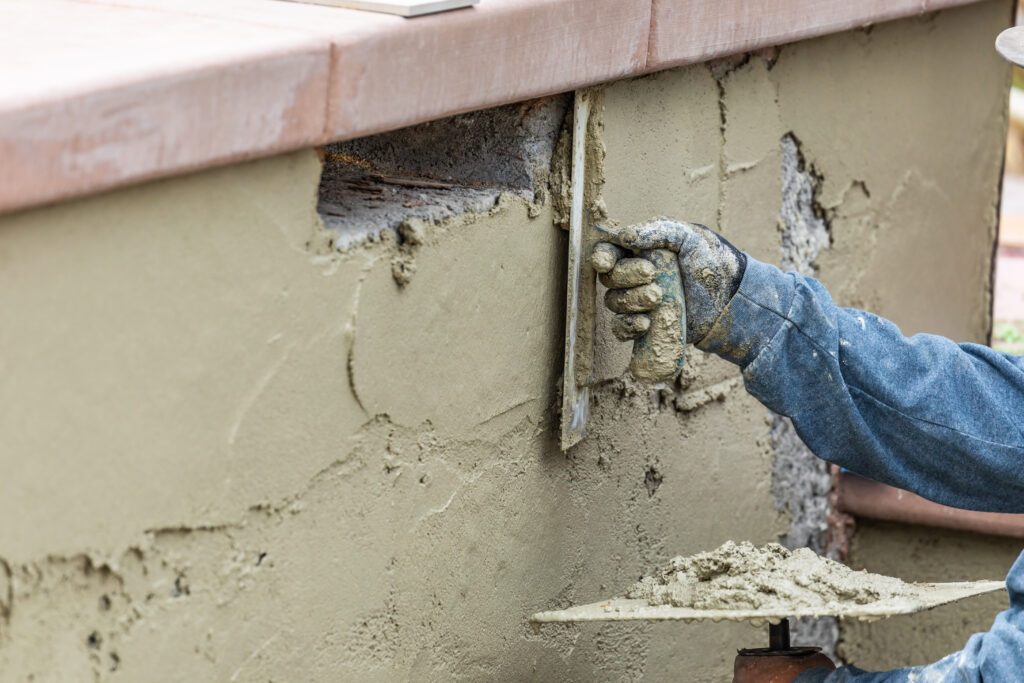 Damaged stucco area being patched on an exterior wall